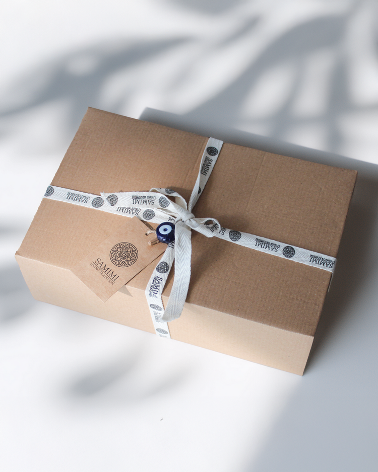 Brun presentbox med vit logoband och etikett, minimalistisk förpackning.