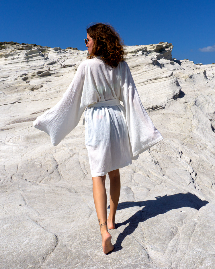 Vit strandkimono i bomull med svart krage, lösa ärmar och skärp i midjan.