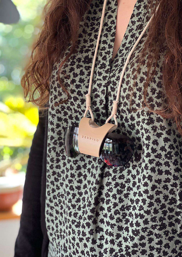 Beige solglasögonbärare i läder runt halsen med svart båge och justerbar rem.