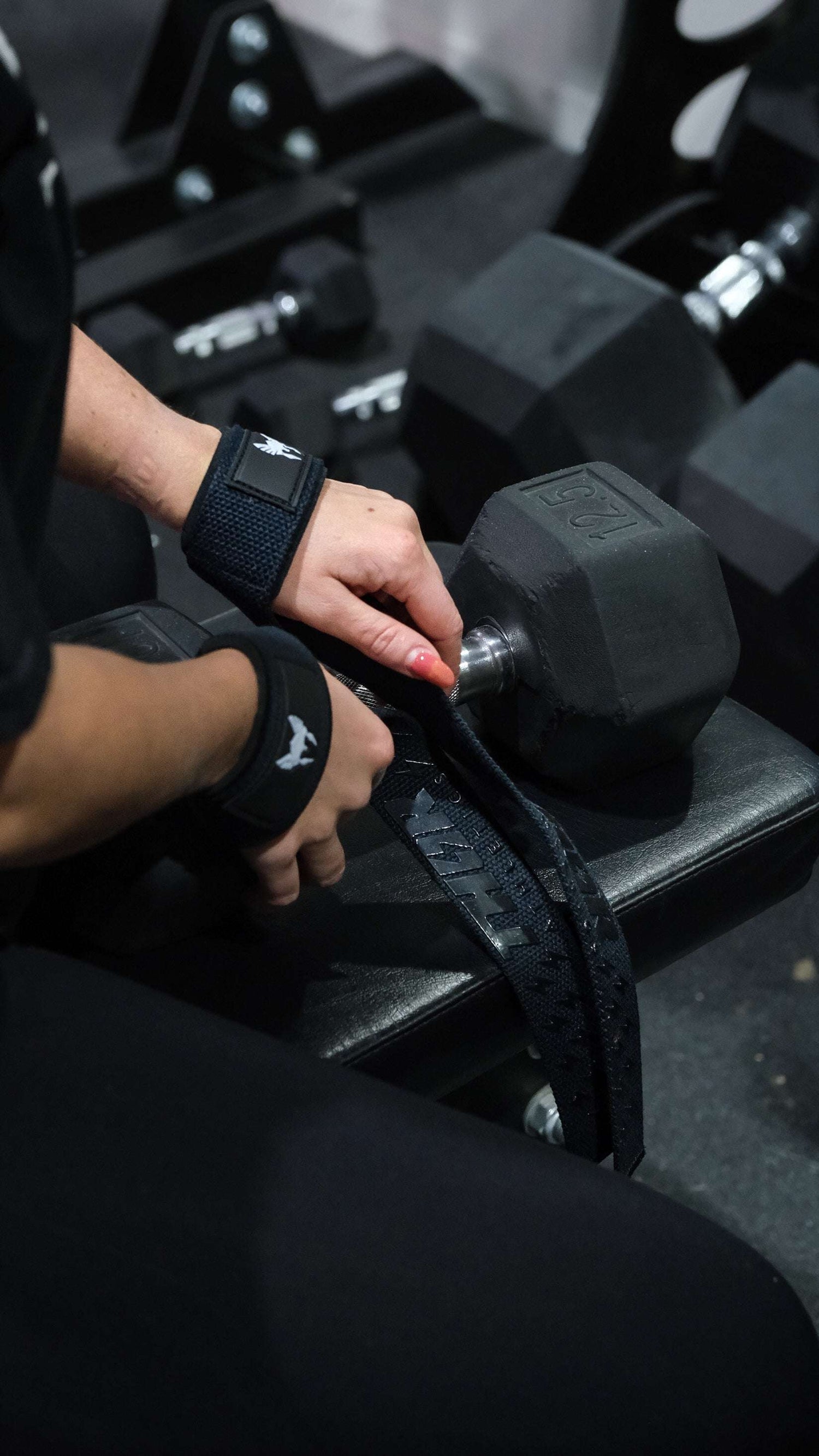 Svart justerbara lyftremmar och handledsstöd i neopren med Viking-logotyp vid hantelstation.