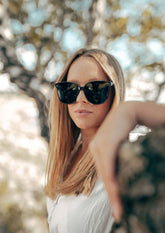 Svarta wayfarer-solglasögon med stor ram och mörka linser från Dahlia Babylon-serien.