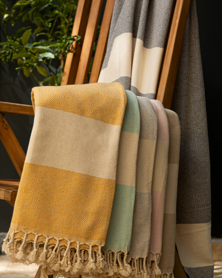 Färgglada pestemal handdukar i breda ränder med tofsar i gula, gröna och rosa toner.