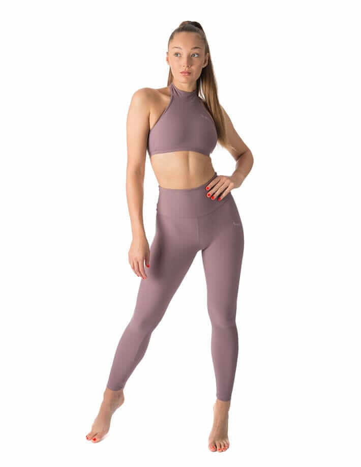 Lila högmidjade yogaleggings med smickrande passform och stretchigt material, modell i träningstopp pose.