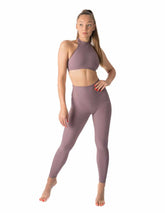 Lila högmidjade yogaleggings med smickrande passform och stretchigt material, modell i träningstopp pose.