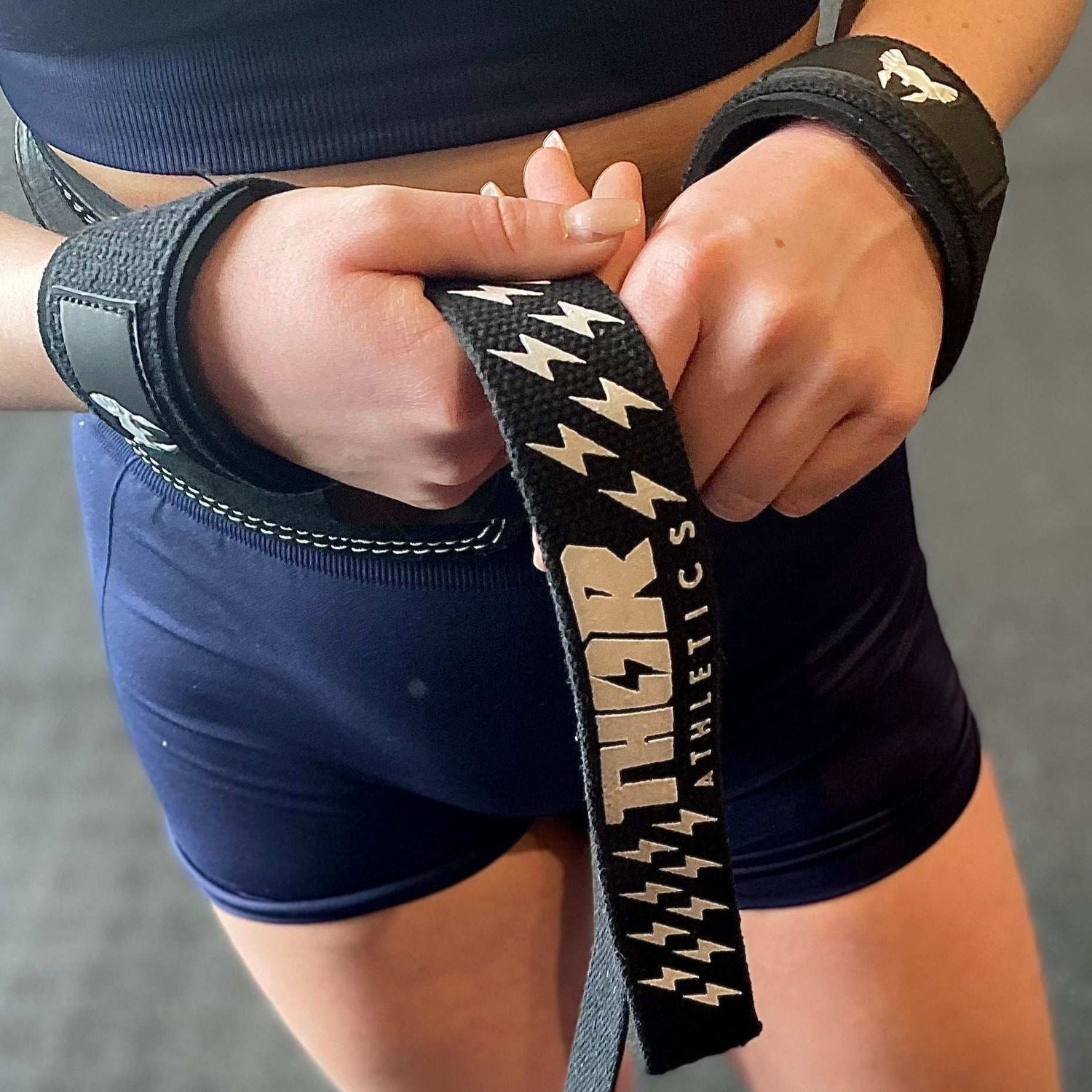 Svarta lyftremmar i bomull med greppmönster och kardborrestängning, ergonomisk design.