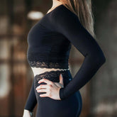 Svart croptopp med lång ärm och spetsdetalj vid midjan i lätt ventilerande tyg.