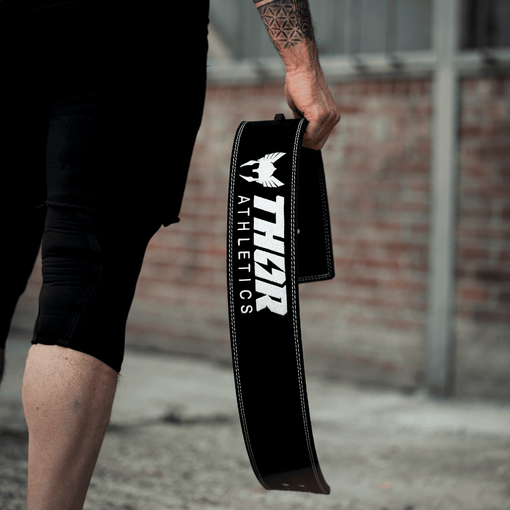 Svart läderlyftarbälte 10mm med vit logotyp THOR Athletics, robust och ergonomiskt designat.