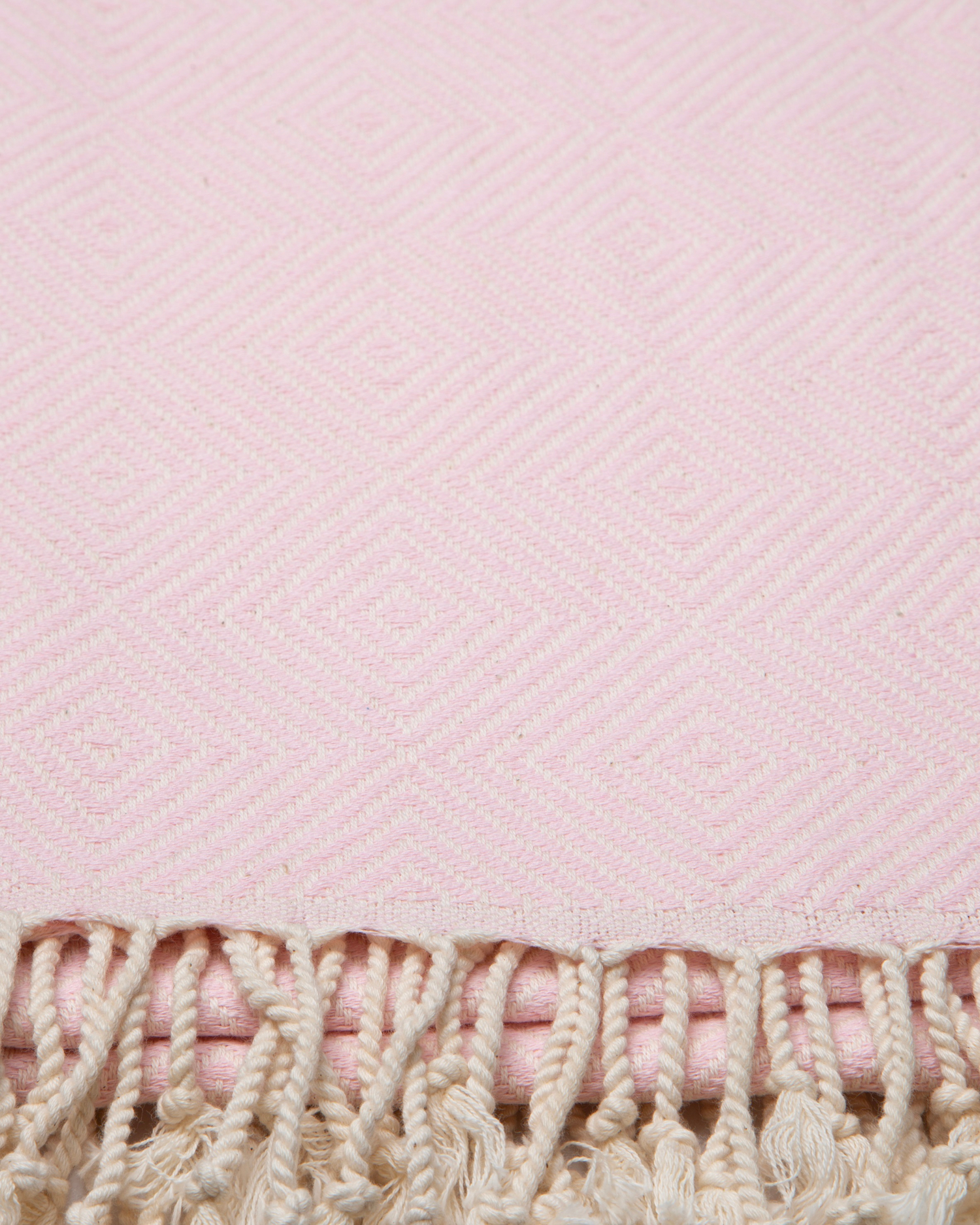 Ljusrosa turkisk bomullsstrandhandduk med geometriskt mönster och fransar.