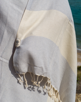 Grå och vit randig hammam strandhandduk med fransar och etikett, lätt och kompakt.