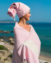 Ljusrosa Hammam-handduk i bomull, lätt och absorberande, lindad runt kvinna vid havet.