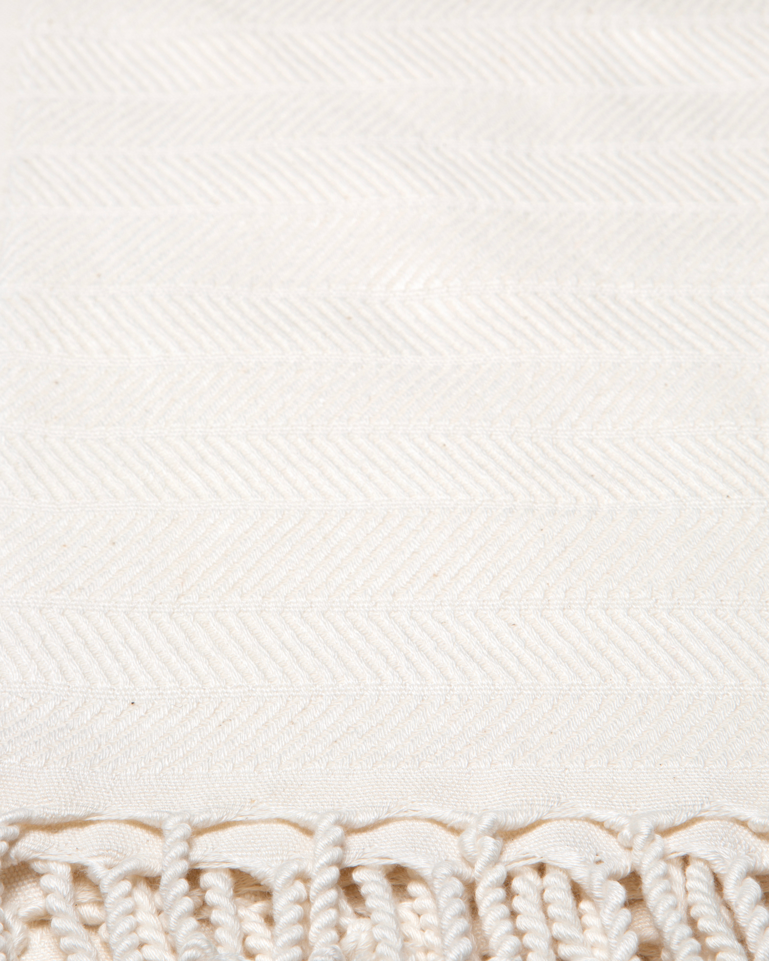 Vit turkisk hammam handduk i bomull och bambu med fiskbensmönster och fransar.