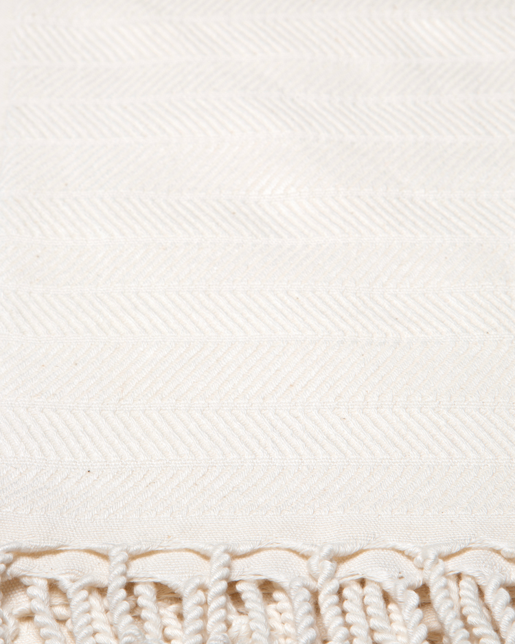 Vit turkisk hammam handduk i bomull och bambu med fiskbensmönster och fransar.