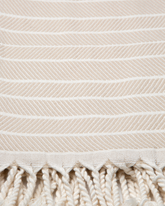 Beige turkisk hammam handduk i bomull och bambu med vitrandigt mönster och tofsar.