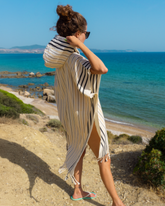 Randig gul och vit strandponcho med huva i lätt bomull vid havet.