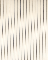 Vit strandponcho med svart smalrandig design i lätt bomullsmaterial.