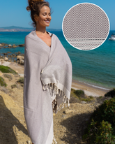 Anthracite svart turkisk hammam-handduk med vit frans, vikbar och lätt, visad vid strandmiljö.