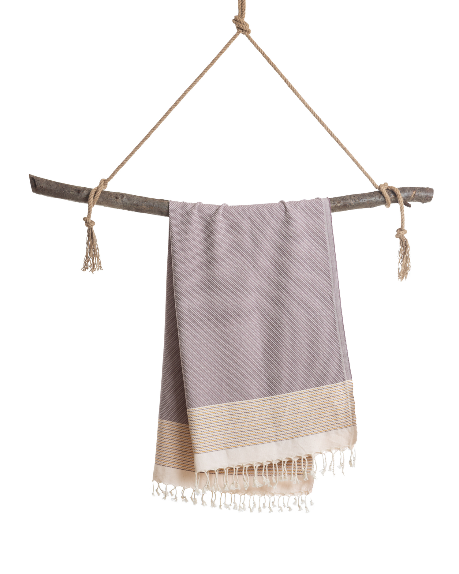 Brun och gul turkisk hammam handduk med fransar hängande på träpinne.