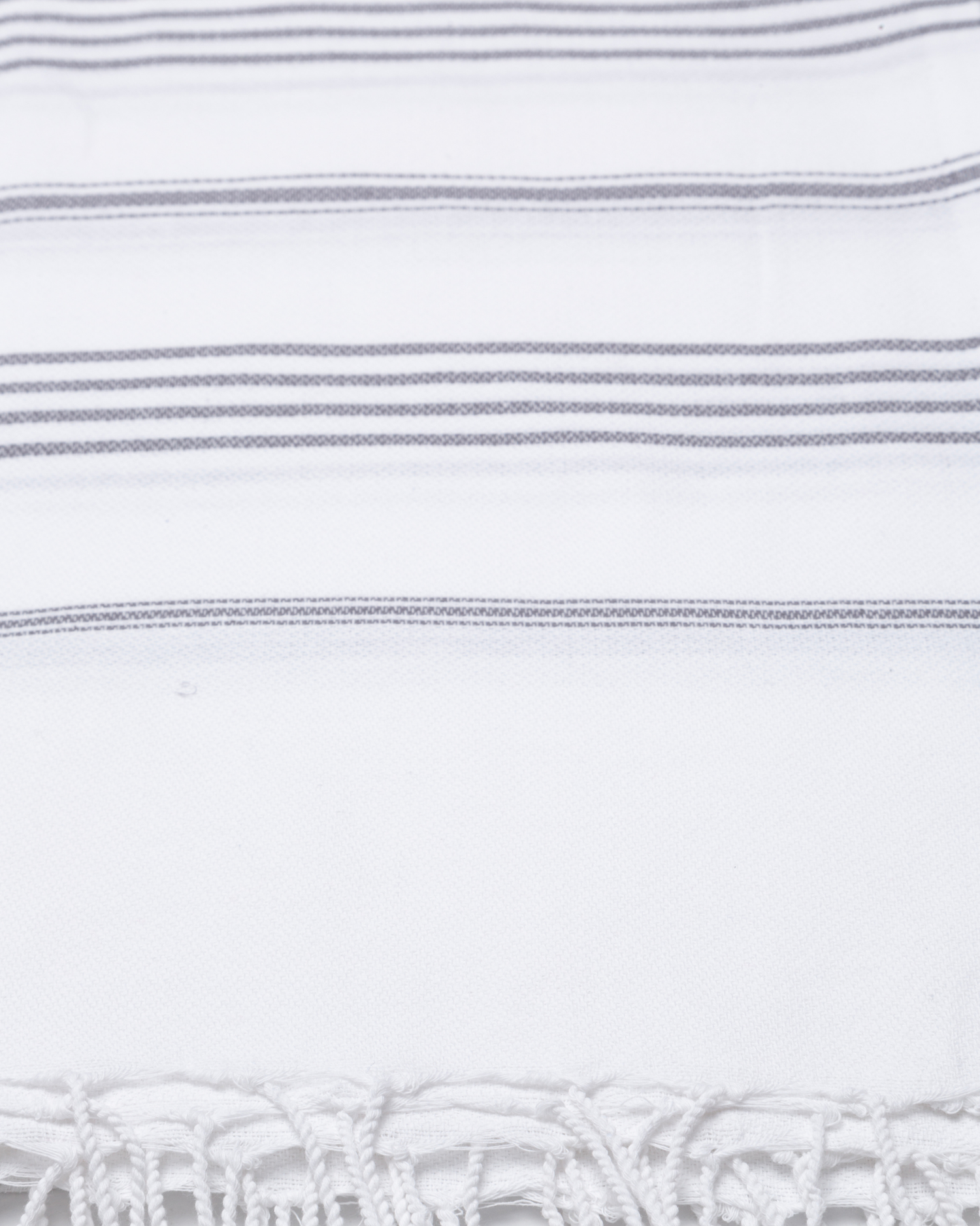 Vit bomullshandduk med grå ränder och fransar i traditionell hammamstil.