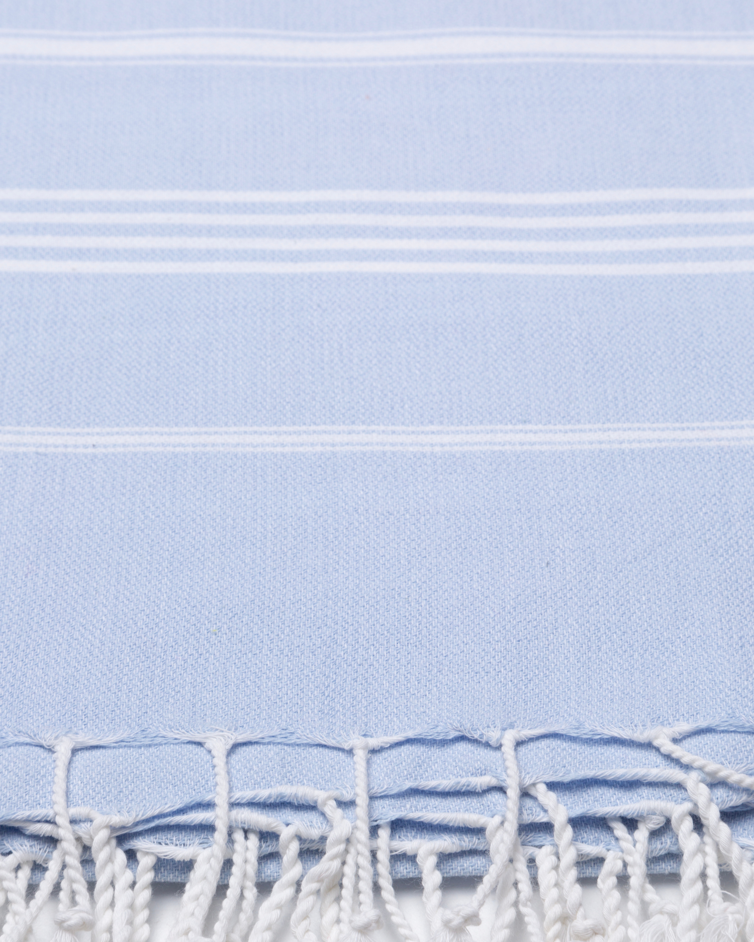 Ljusblå bomullshandduk med vita ränder och fransar, lätt och kompakt peshtemal-textur.