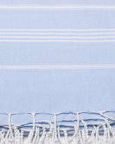 Ljusblå bomullshandduk med vita ränder och fransar, lätt och kompakt peshtemal-textur.