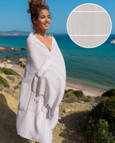 Beige randig hammam handduk i bomull med fransar, svept runt kvinna vid havet.