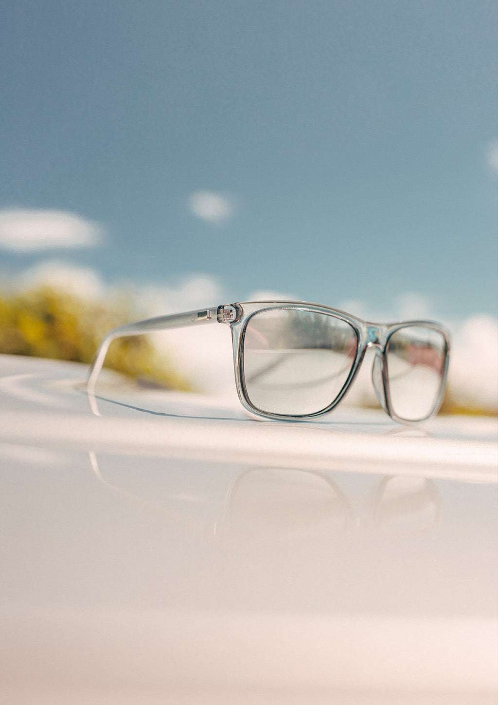 Wayfarer-solglasögon med transparent plastbåge och silverfärgade aluminiumskalmar, klara linser och färgstarka detaljer.