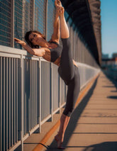 Svarta caprileggings med hög midja och stretchmaterial på kvinna i gymnastikpose vid räcke utomhus.