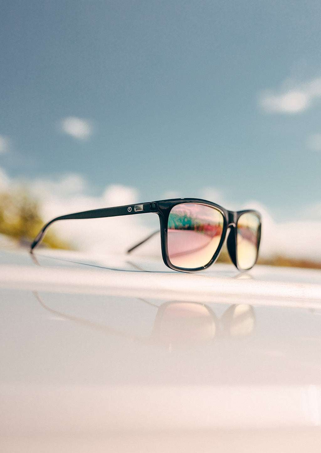 Svarta wayfarer-solglasögon med rosa spegelglas och aluminiumskalmar, plastframdel med färgdetaljer.