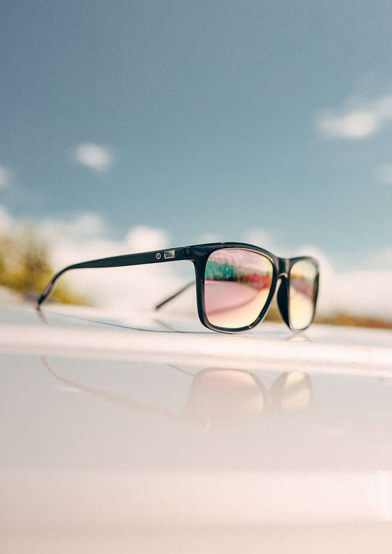 Svarta wayfarer-solglasögon med rosa spegelglas och aluminiumskalmar, plastframdel med färgdetaljer.