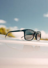 Svarta wayfarer-solglasögon med aluminiumdetaljer och tonade linser, elegant design.