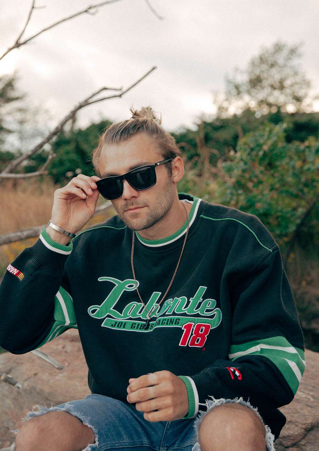 Svarta wayfarer-solglasögon med aluminiumram och tjocka stänger på man i casual sweatshirt utomhus.