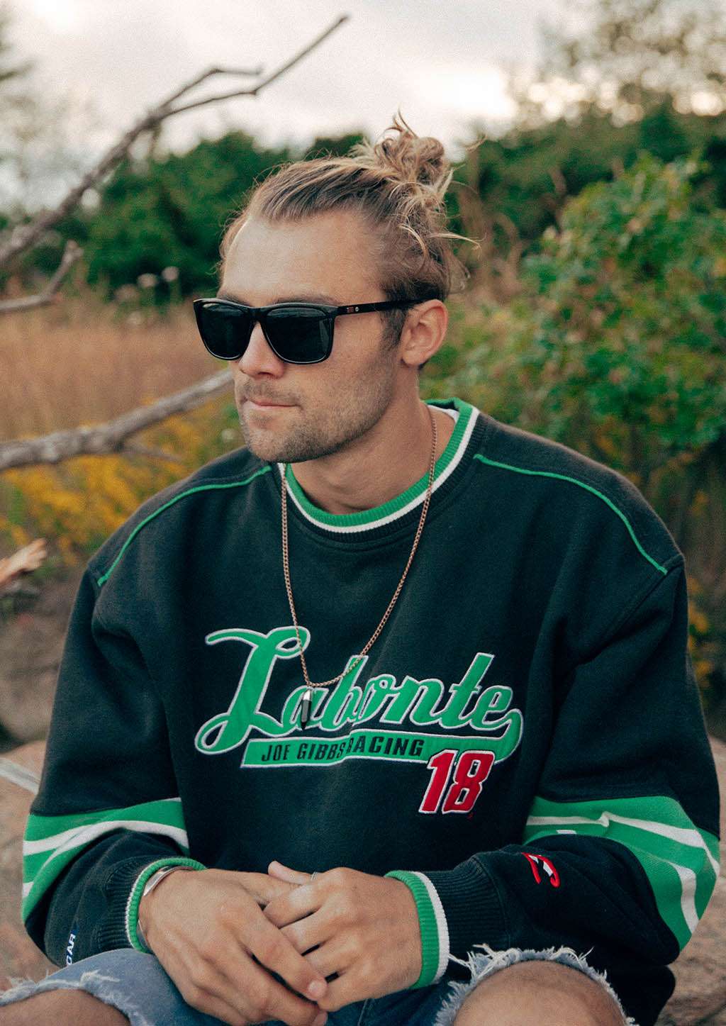 Svarta Wayfarer-solglasögon med aluminiumdetaljer på man i grön och svart tröja.