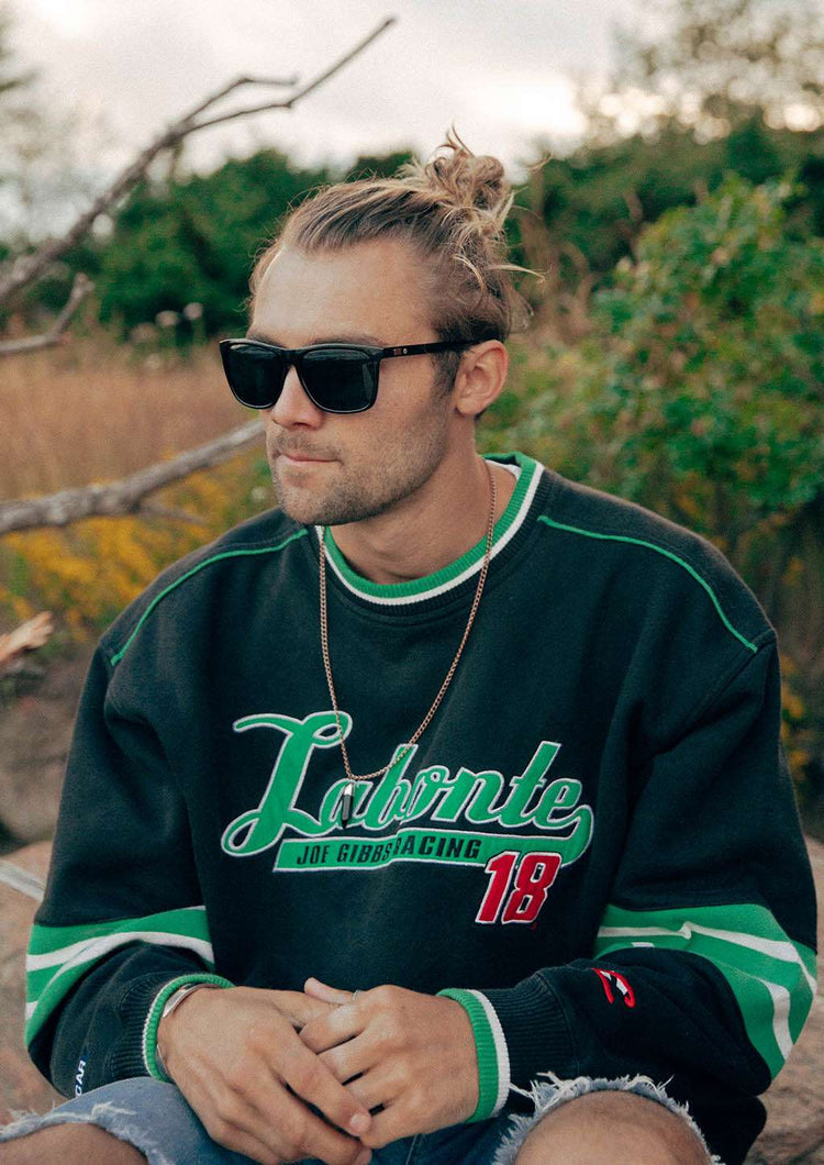 Svarta Wayfarer-solglasögon med aluminiumdetaljer på man i grön och svart tröja.