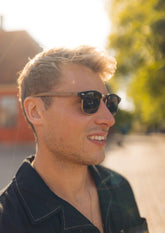 Svarta Clubmaster-solglasögon med rosenträram och polariserade spegellinser på man.