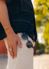 Svarta Clubmaster-solglasögon med spegellinser i handgjort rosenträ hållna i hand vid ljus bakgrund.