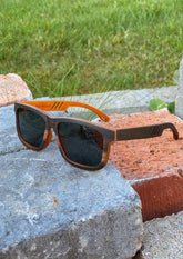 Svarta träsolglasögon med wayfarer-design och orange insida, handgjorda i rosenträ.