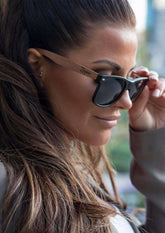 Svarta Wayfarer-solglasögon med rosenträbågar och mörka polariserade linser.