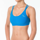 Blå sport-bh med dubbla axelband och vit logga på vänster sida, slät design.