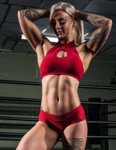 Röd sport-bh med hög halsringning och nyckelhålsdetalj i elastiskt, fuktavvisande tyg.