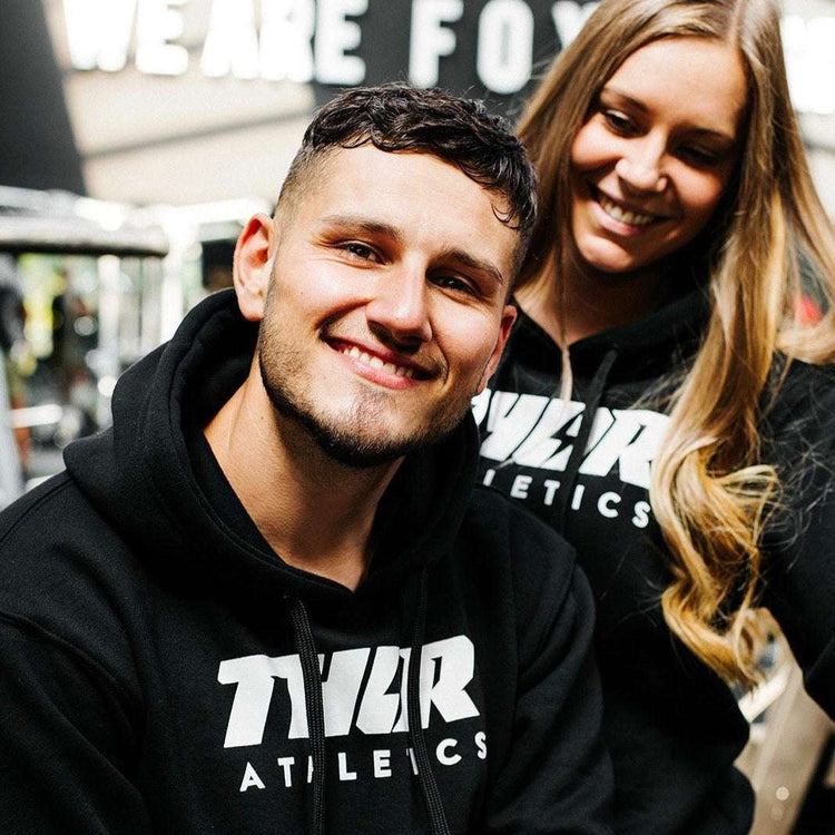 Svart hoodie med vit tryckt text, rymlig huva och känguruficka i mjukt tyg.